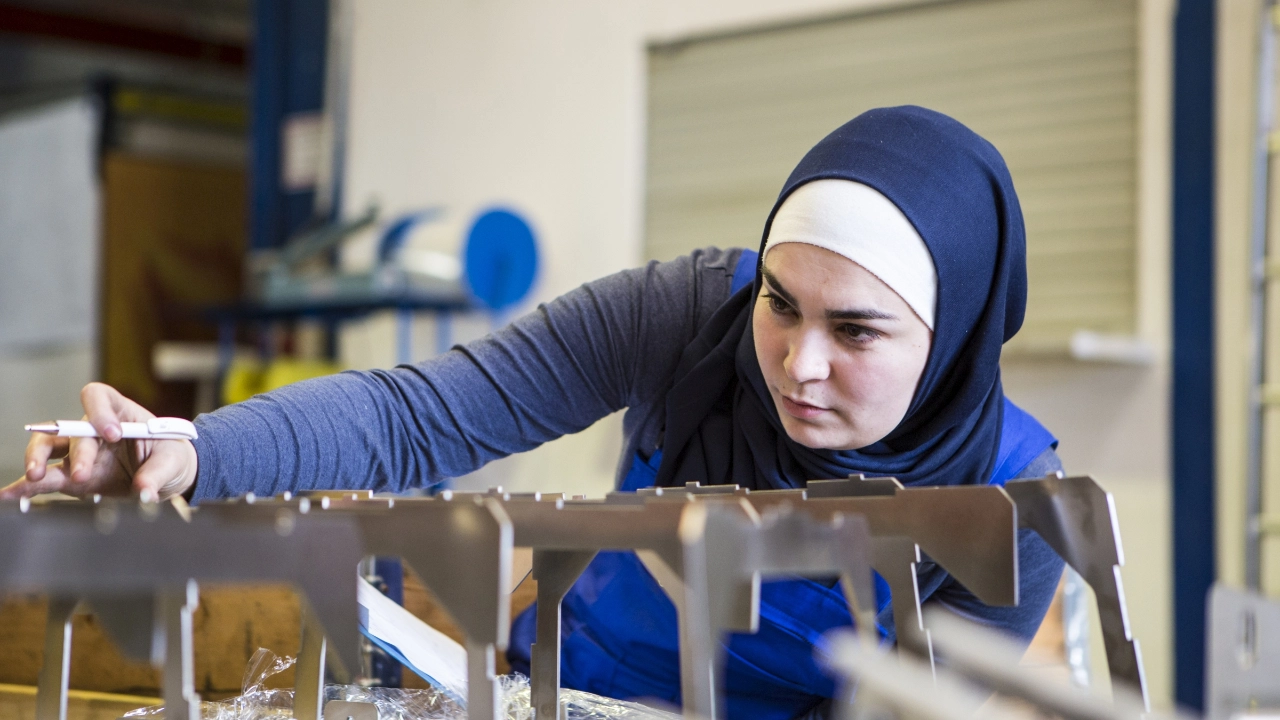 Eine Auszubildende kontrolliert Metallteile.