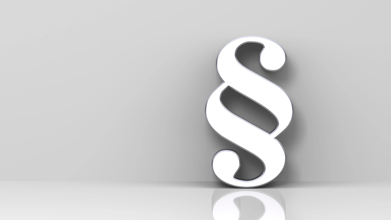 Ein stehender silberner Paragraph vor einer weißen Wand