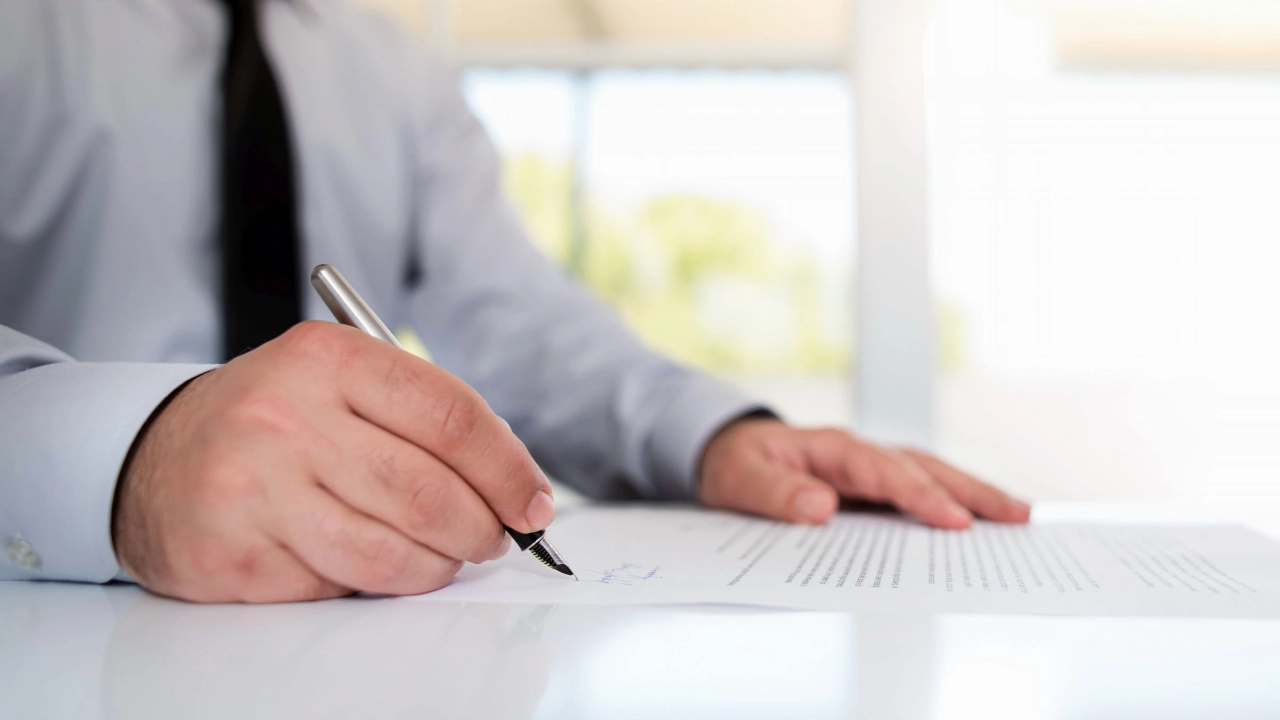Mann im Annzug unterschreibt ein Dokument