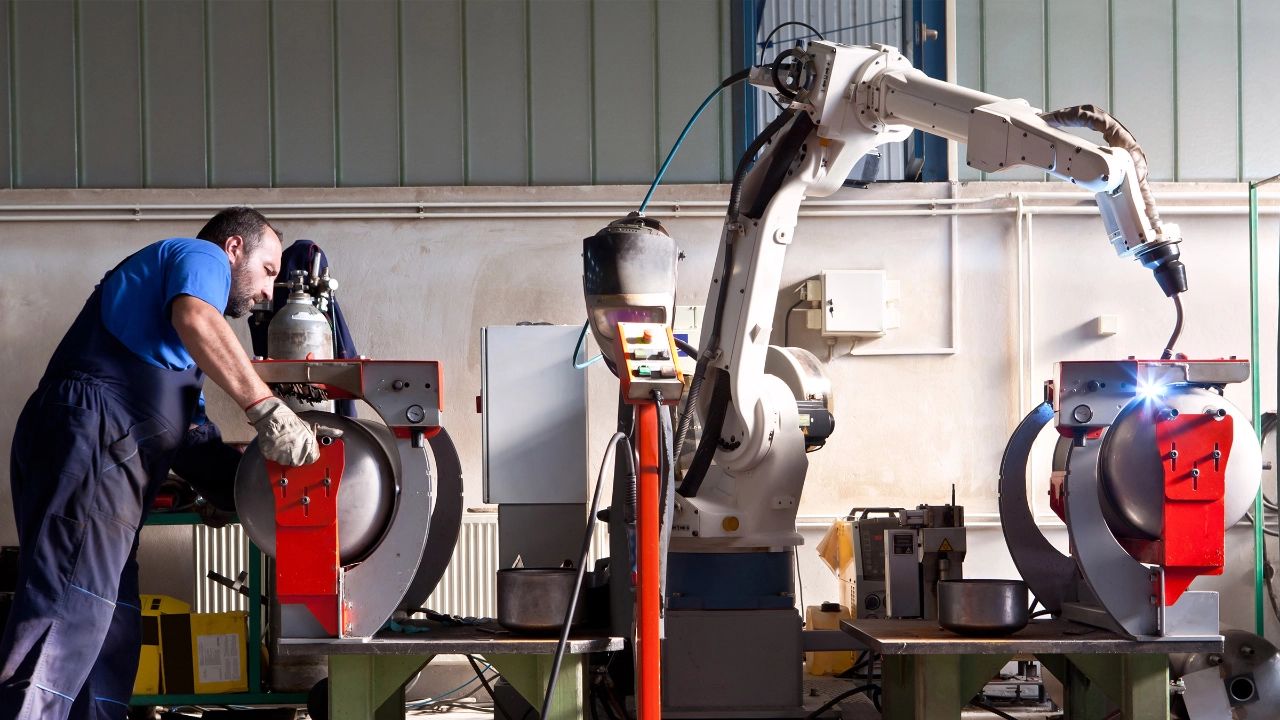 Ein Schweißroboter schweißt Kessel in einer Werkshalle 