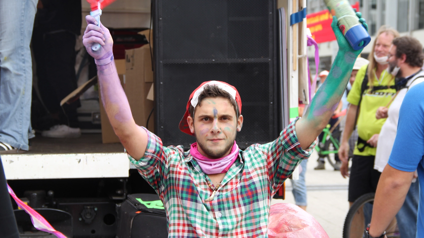Junger Mann hat Spraydosen in der Hand und ist auf einer Demo.