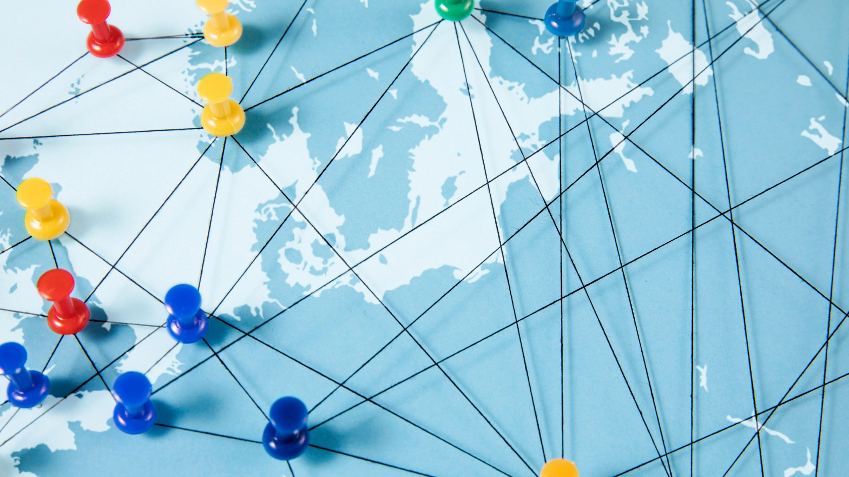 Auf einer Europakarte sind Fäden mit Pins gespannt