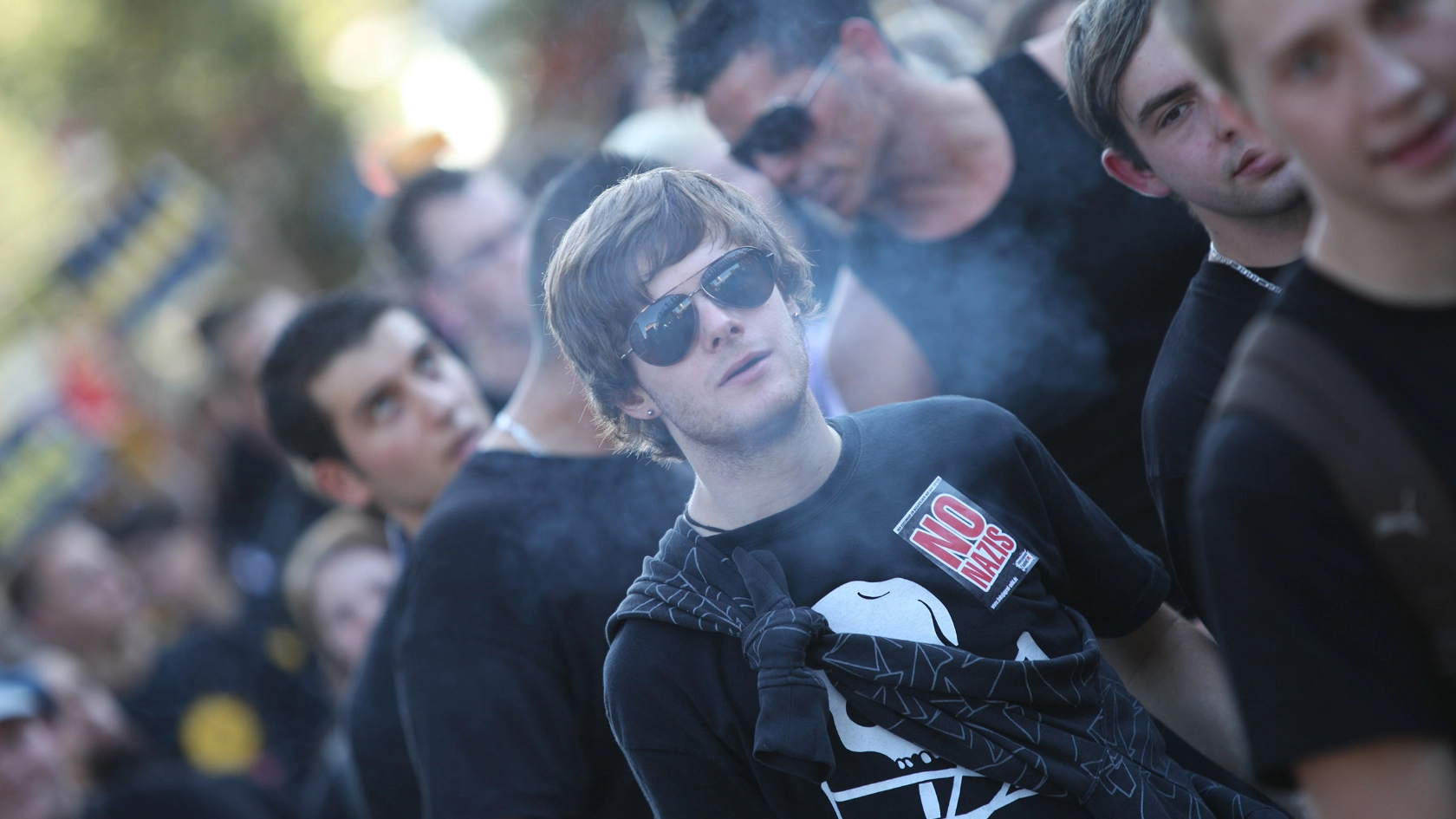Junger Mann mit Sonnebrille läuft zwischen vielen anderen auf einer Demo mit