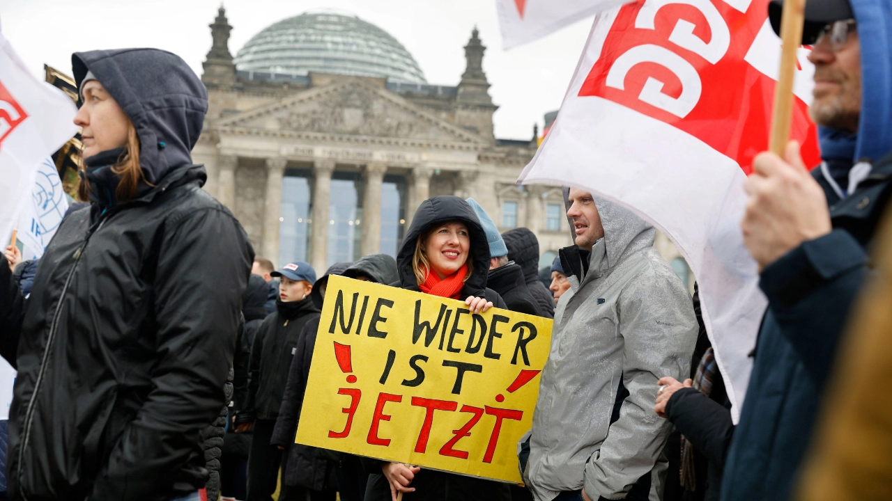 In der Menschenmenge bei einer Demo trägt eine Frau ein Schild mit der Aufschrift „Nie wieder ist jetzt“.