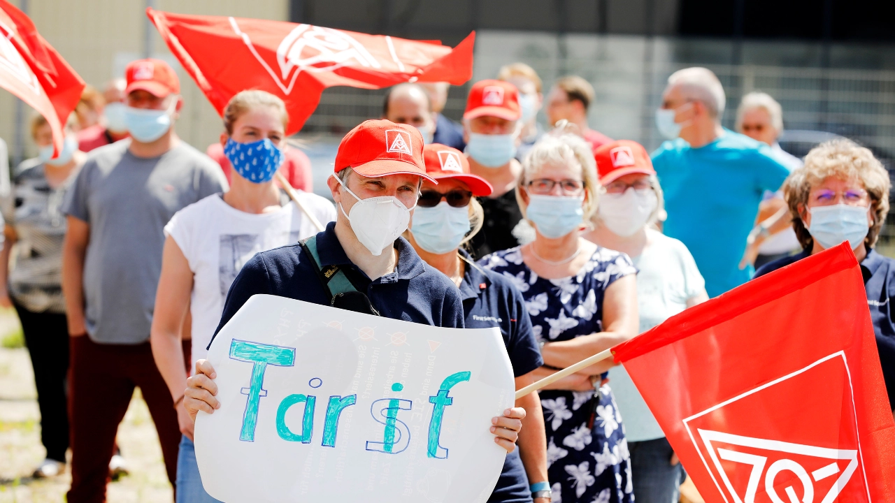 Beschäftigter mit Plakat und Fahne auf einer Demonstration