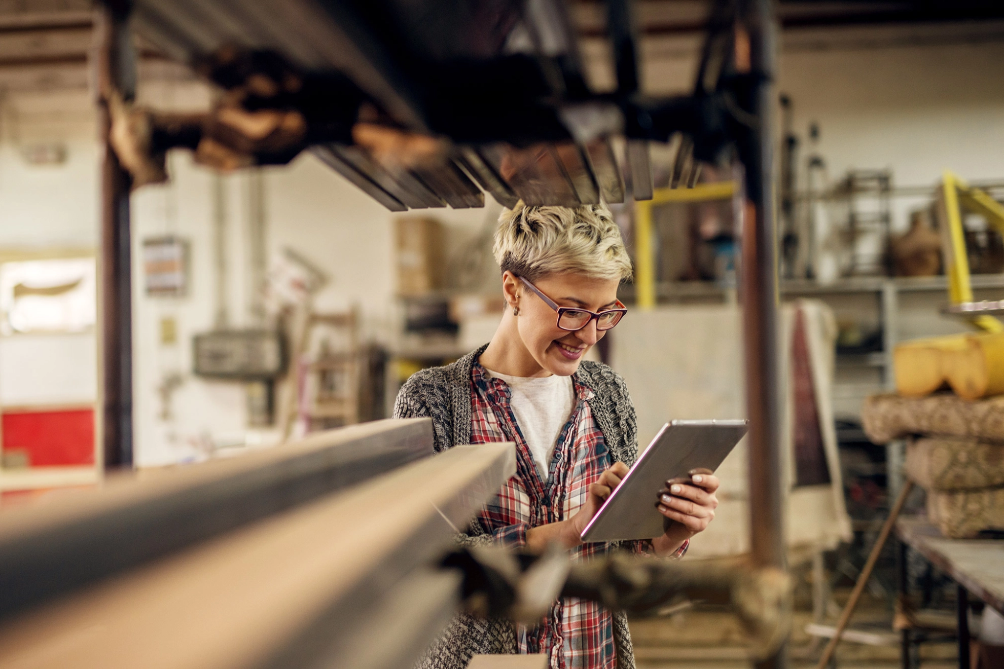 Junge Frau in der Werkstatt bedient ein Tablet.