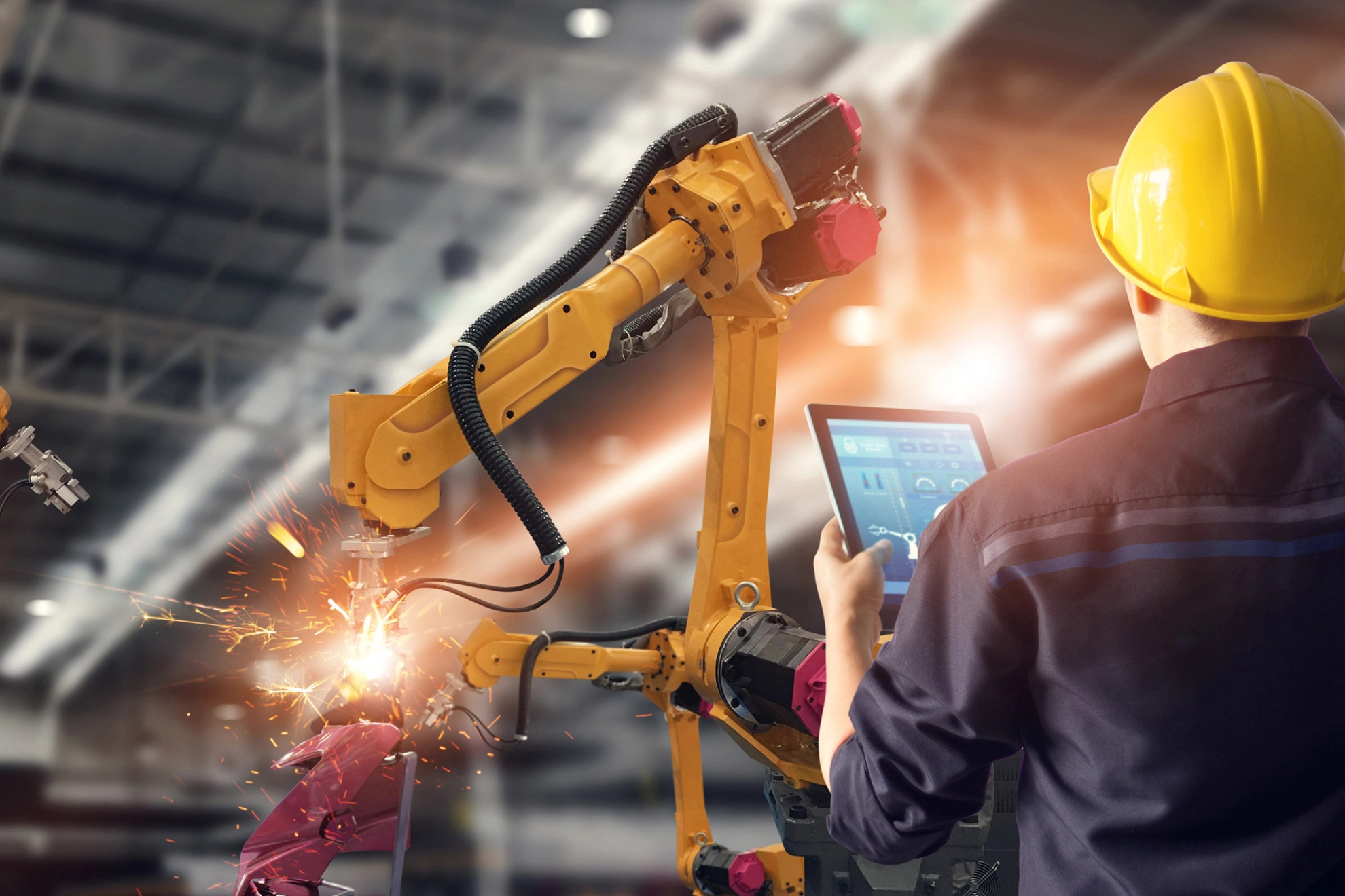 Ingenieur steuert mit Tablet einen Schweißroboter