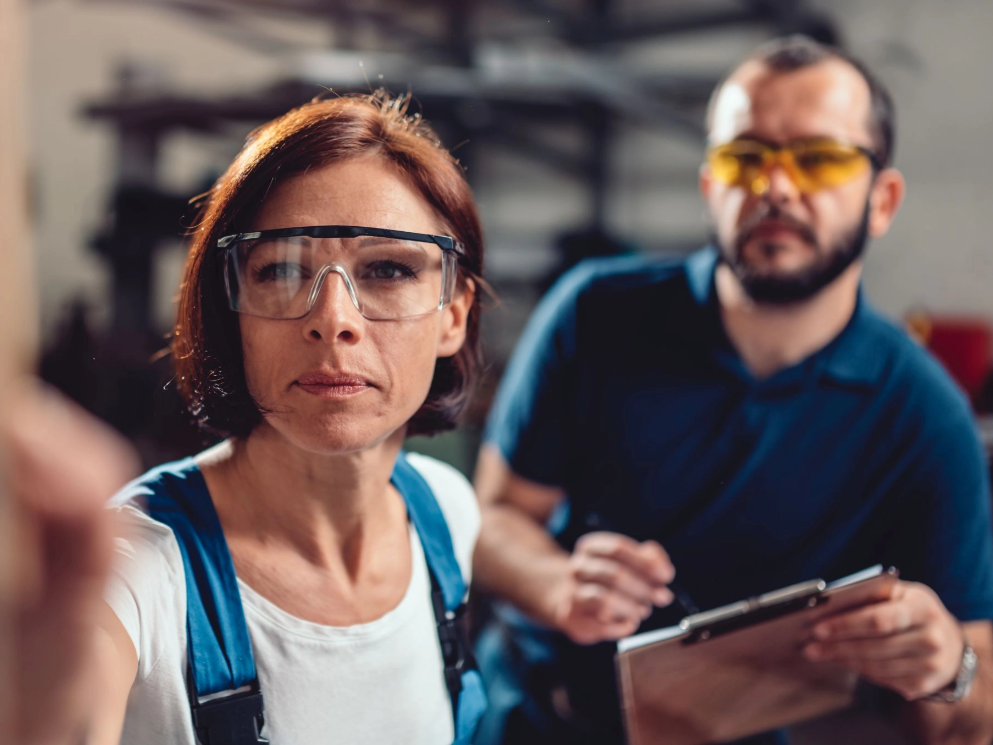 Arbeitnehmerin und Arbeitnehmer prüfen gemeinsam eine Maschine oder Bestand