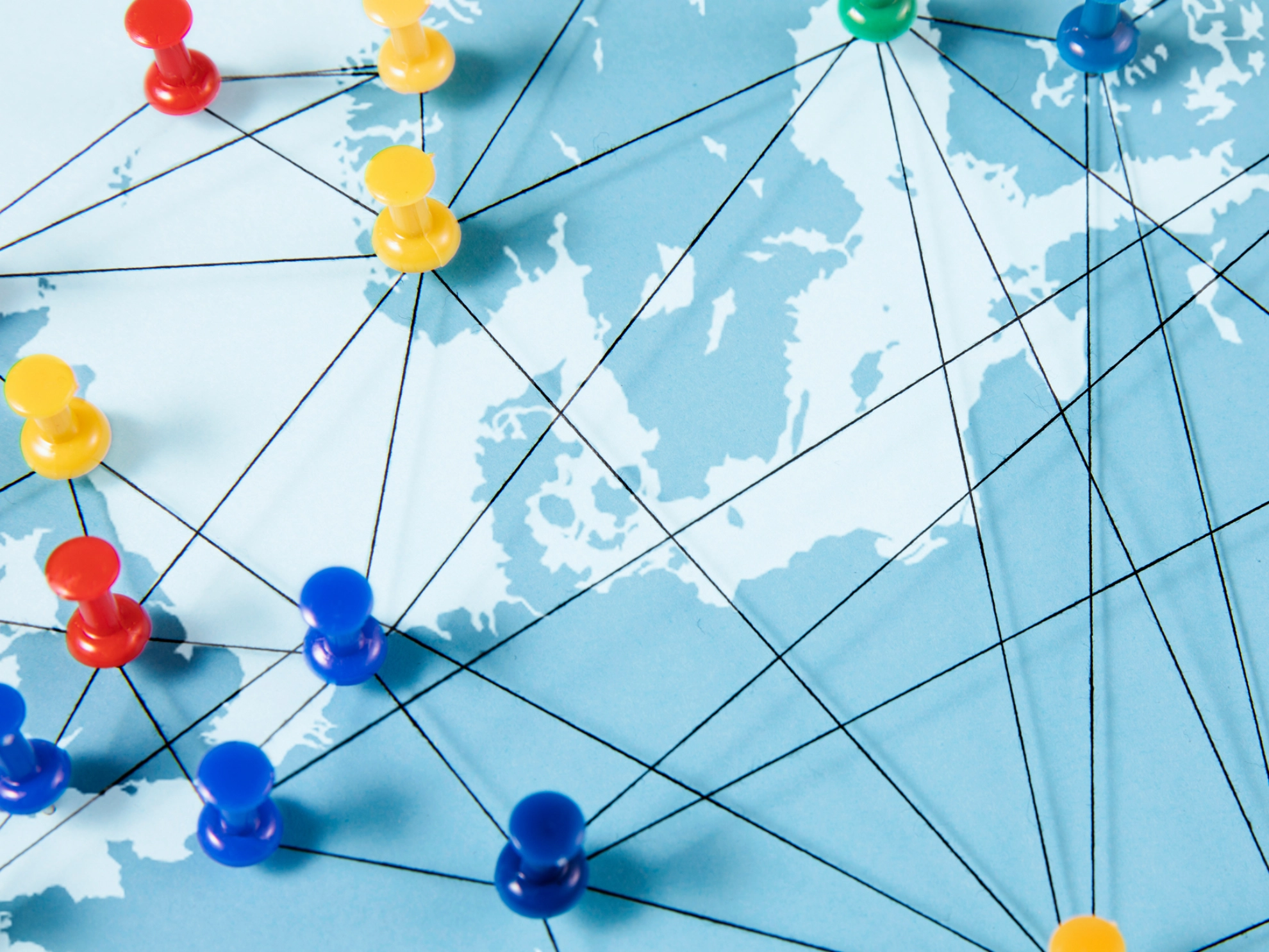 Auf einer Europakarte sind Fäden mit Pins gespannt