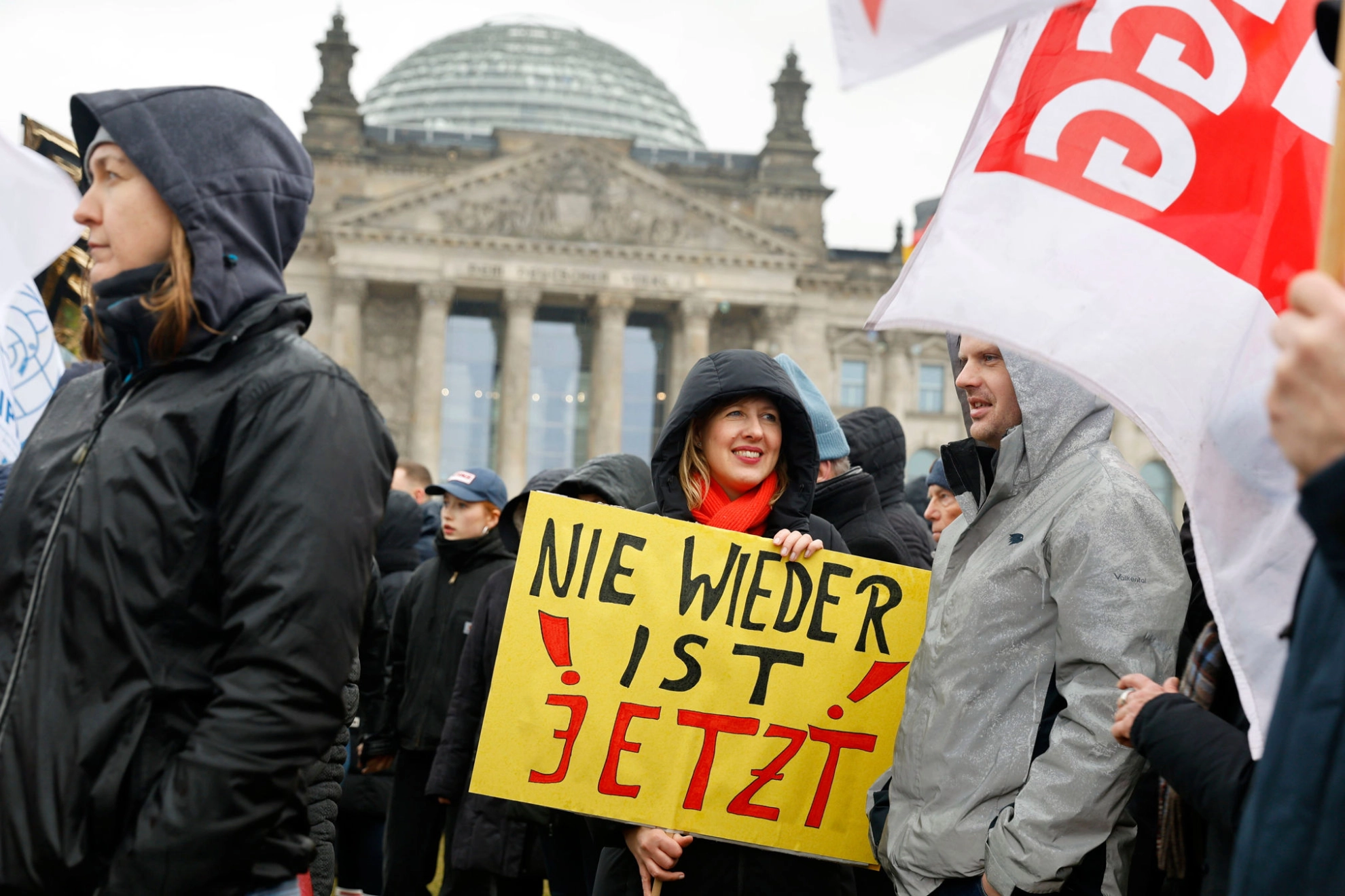 In der Menschenmenge bei einer Demo trägt eine Frau ein Schild mit der Aufschrift „Nie wieder ist jetzt“.