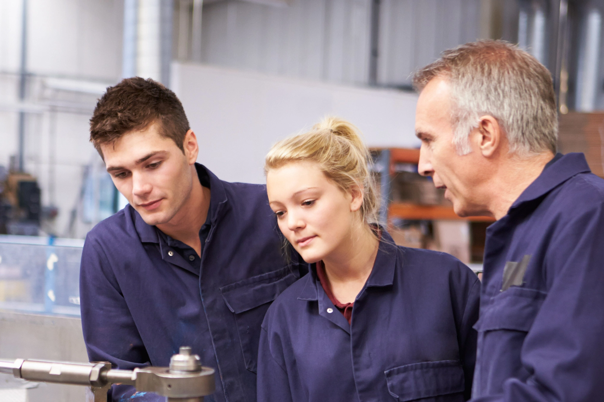 Ingenieur erklärt zwei Auszubildenden eine Maschine