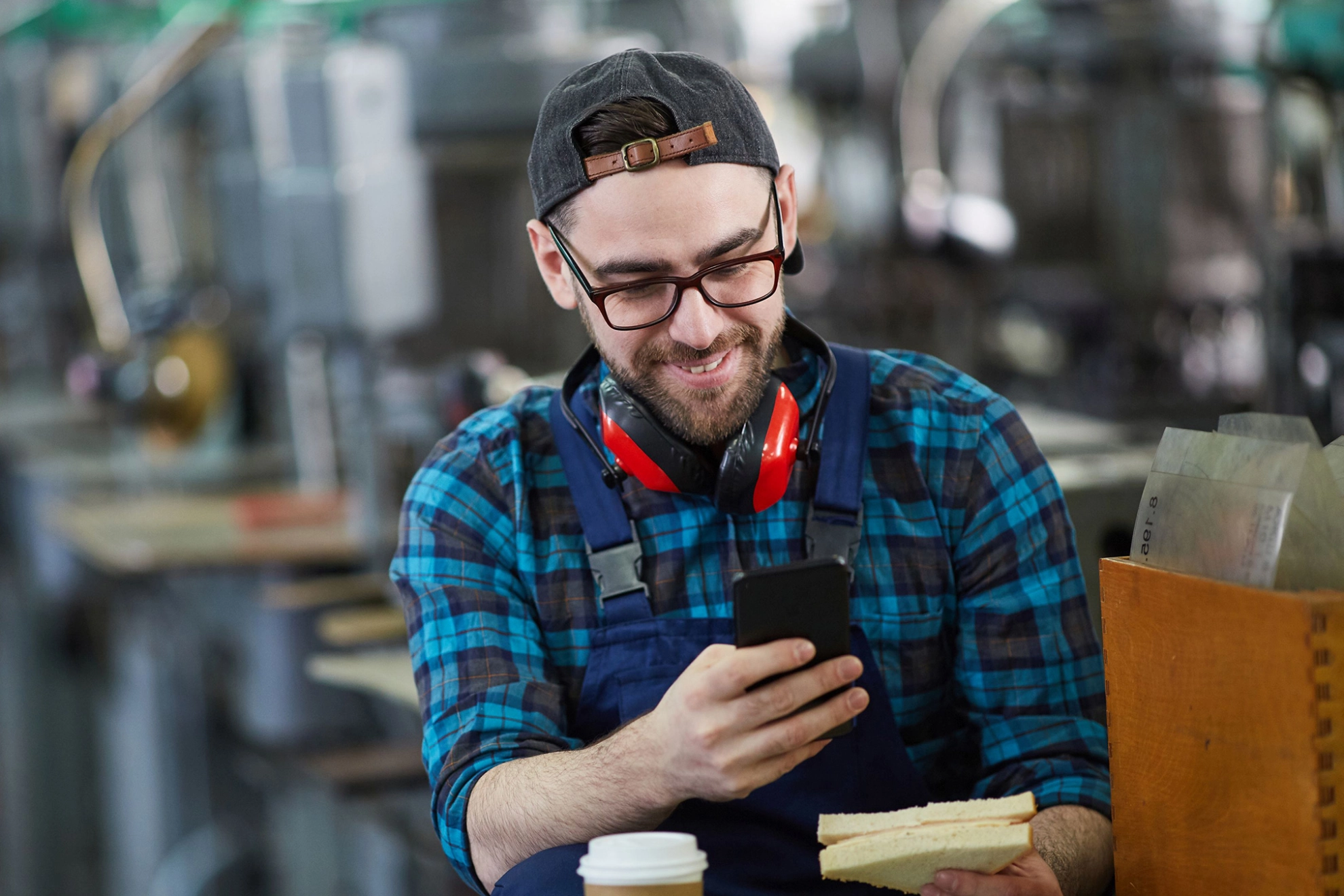 Arbeiter schaut während einer Pause auf sein Smartphone