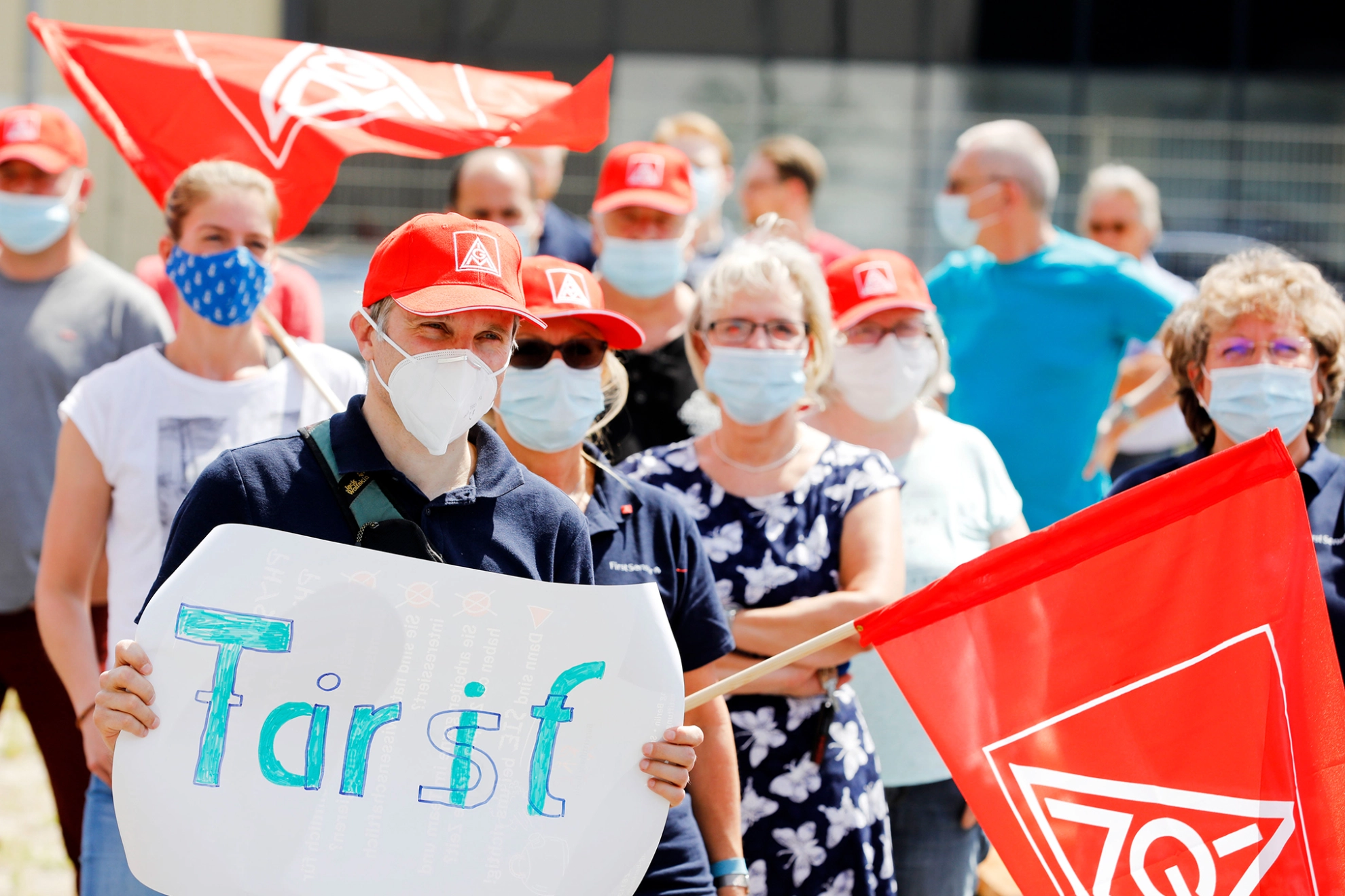 Beschäftigter mit Plakat und Fahne auf einer Demonstration