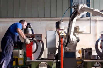 Ein Schweißroboter schweißt Kessel in einer Werkshalle 