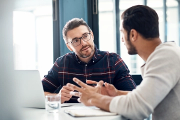 Zwei Männer im Gespräch sitzen an einem Tisch