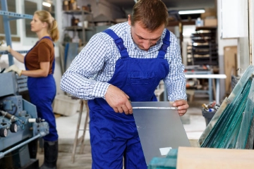 Glaser prüft Glasgröße mit Maßband