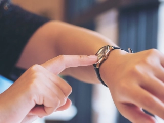 Eine Frau zeigt auf ihre Armbanduhr