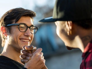 Zwei junge Männer geben sich freudig die Hand