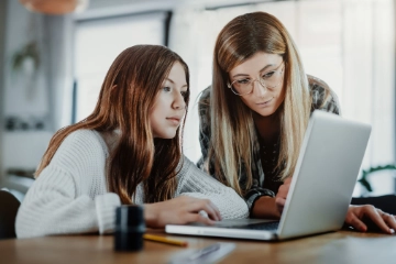 Mutter und Tochter schauen gemeinsam auf einen Laptop