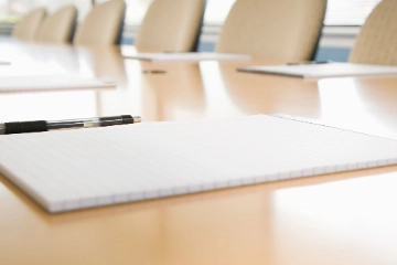 Blöcke und Stifte liegen bereit auf einem unbesetzten Konferenztisch