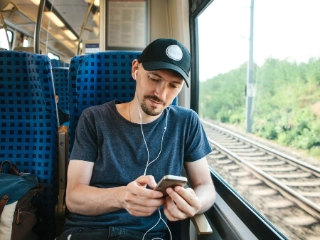 Junger Mann mit Smartphone in der Bahn