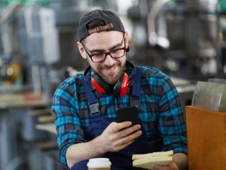 Arbeiter schaut während einer Pause auf sein Smartphone