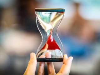 Eine Sanduhr, durch die roter Sand rinnt.